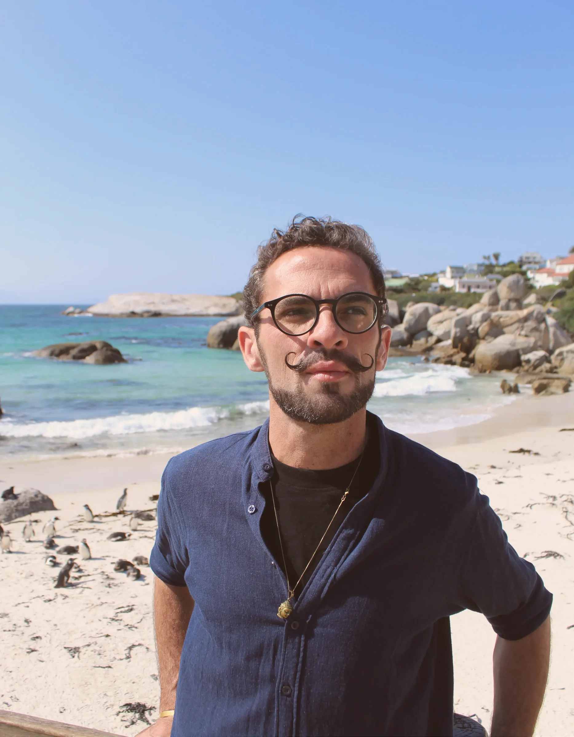 Mikhail Schrader, founder of Travel African Time, beside the ocean at Boulders Beach Penguin Colony, Cape Town, South Africa. Viewing the endangered African Penguin.