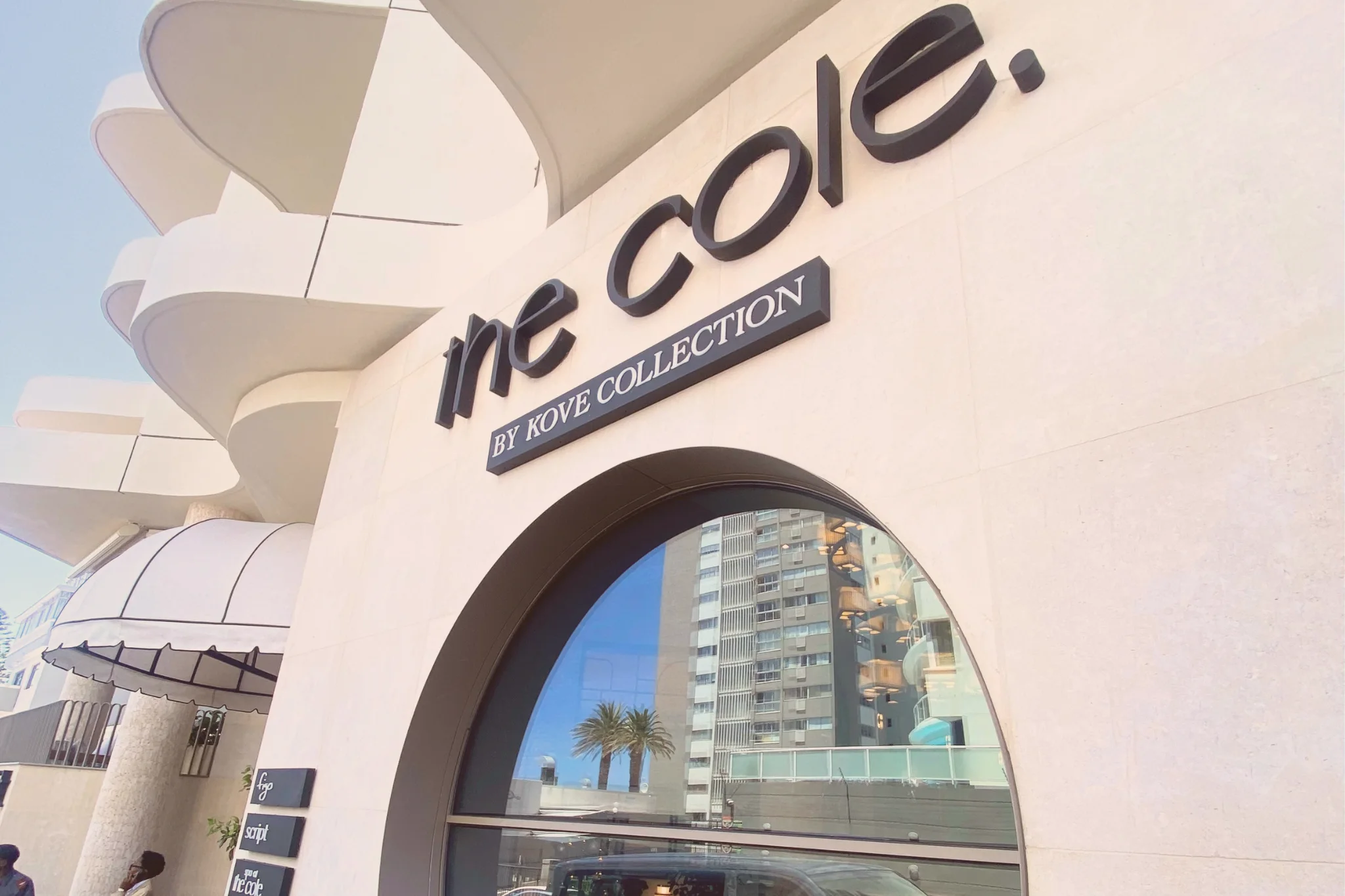 The Cole by Kove Collection in Sea Point, Cape Town, with black signage, a pale stone façade, curved balconies and a large arched window.