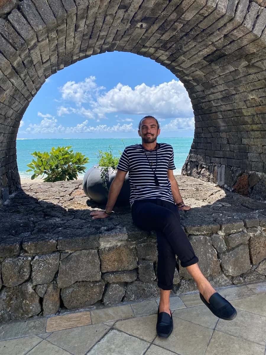 Mikhail beneath a stone arch overlooking the sea in Mauritius