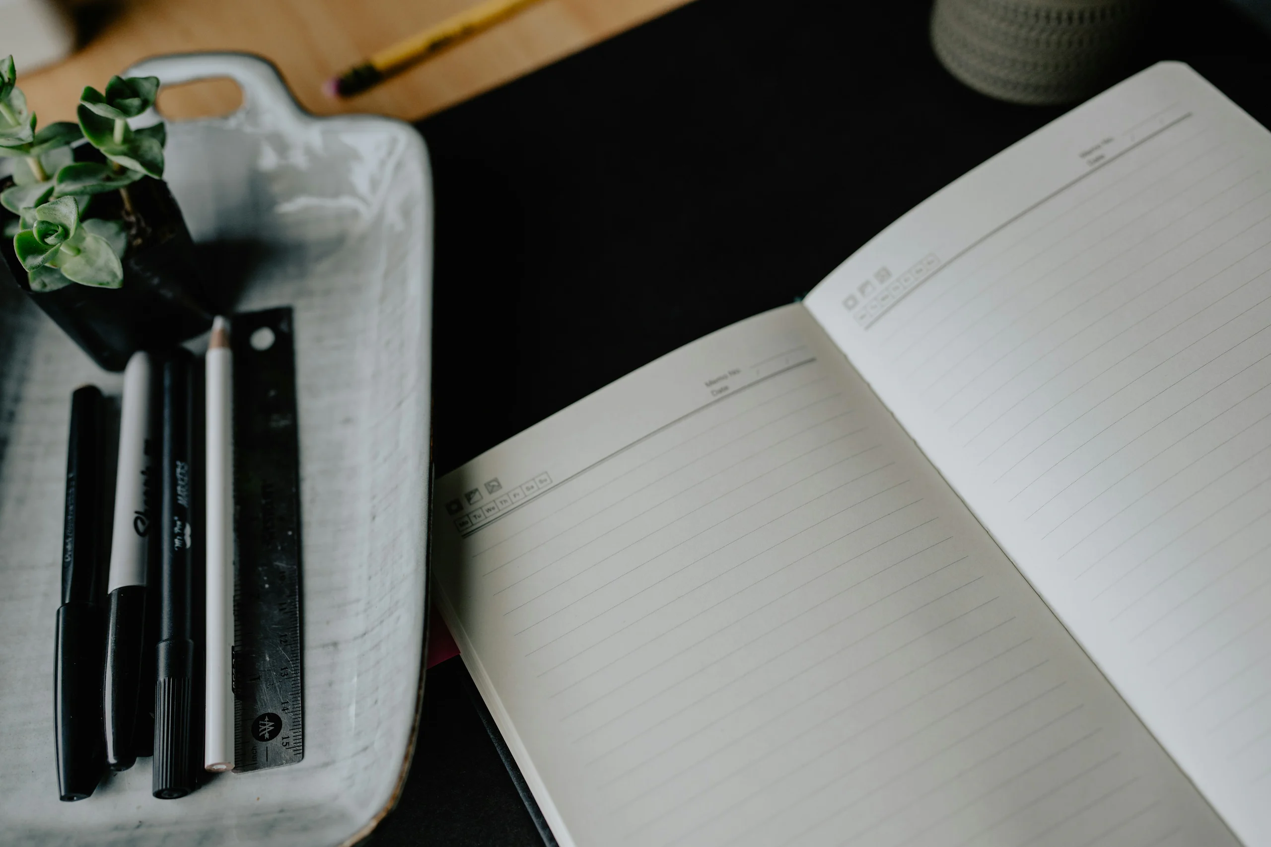 An open journal and writing tools arranged on a considered desk
